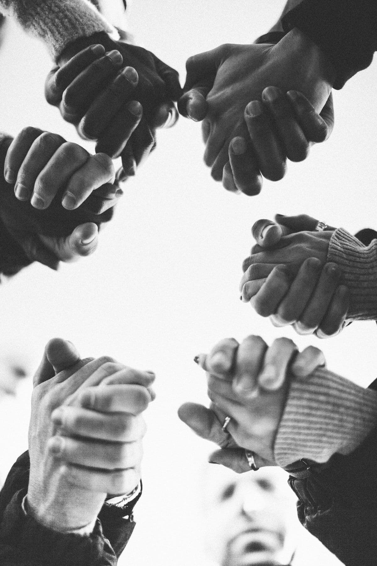 Hands joined in unity, viewed from below against the sky